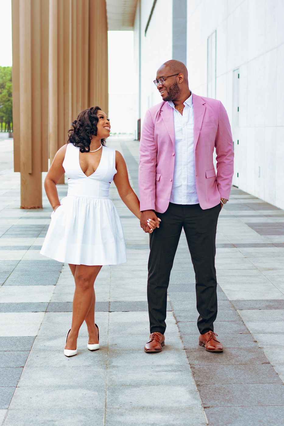 Couple holding hands in white dress and rose blazer