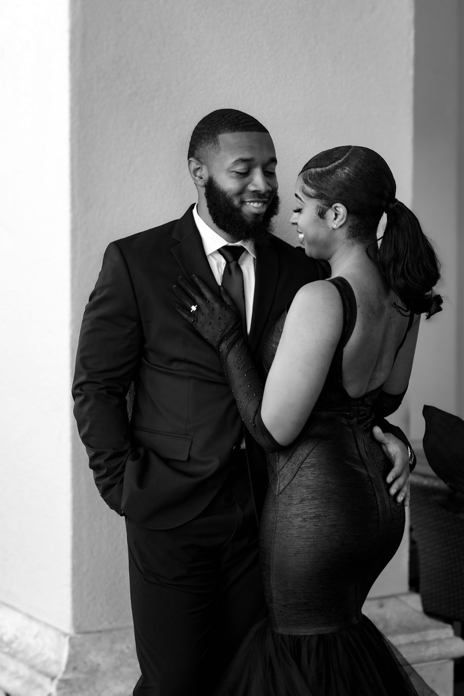 Formal black-tie couple sharing a smile in black and white
