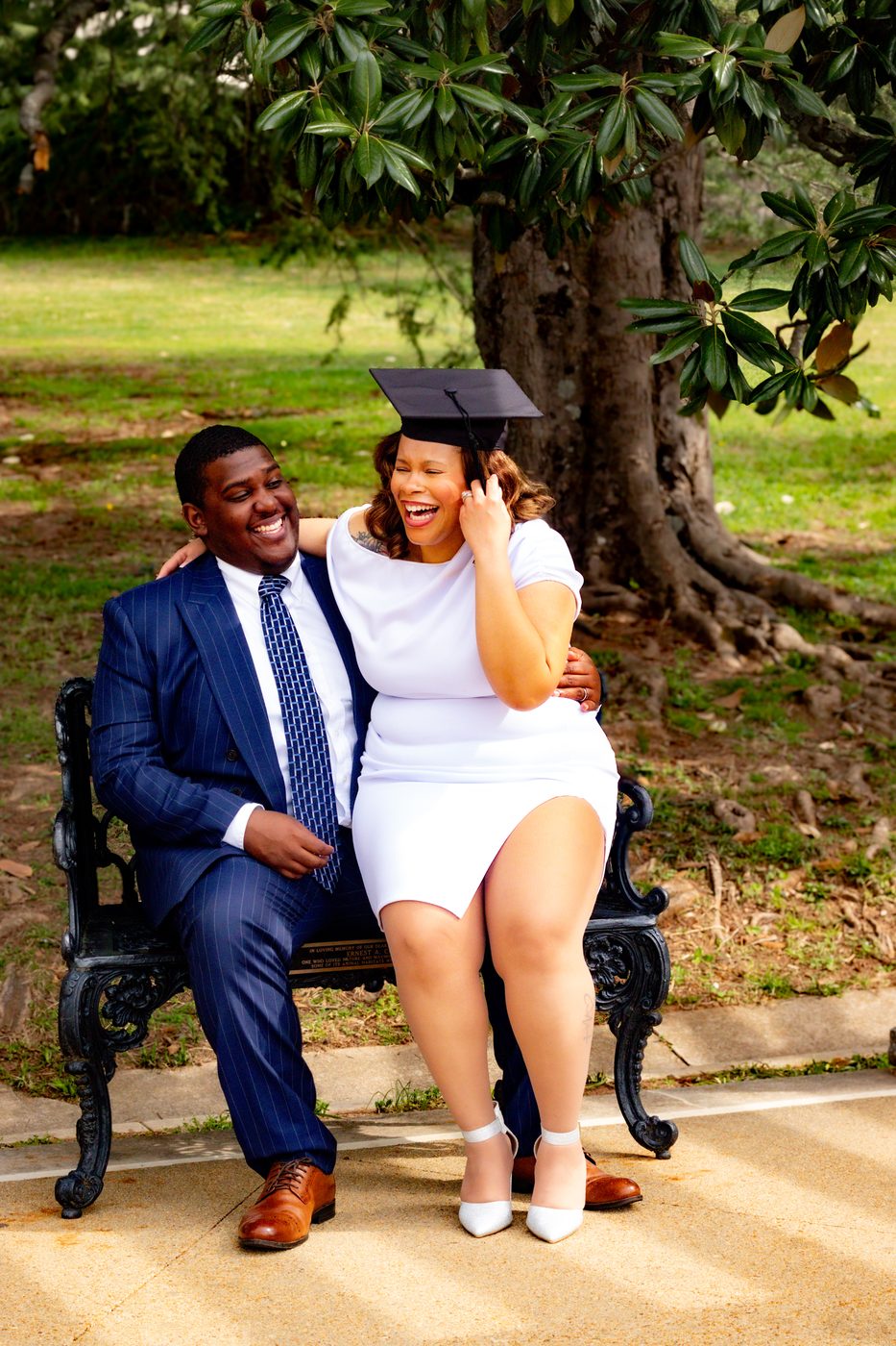 Graduate laughing with partner on a garden bench