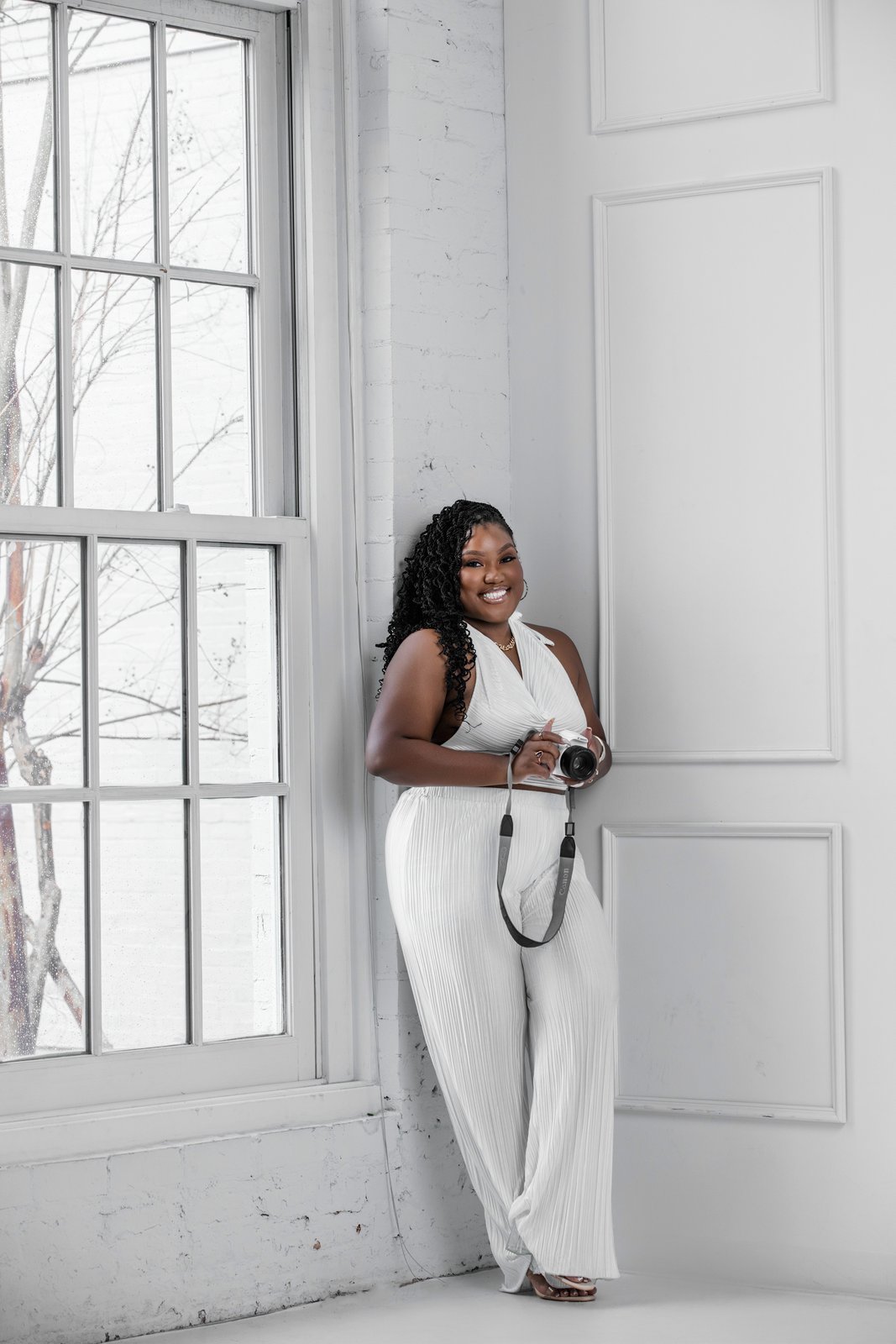 Patty Barham smiling with her camera in a bright studio
