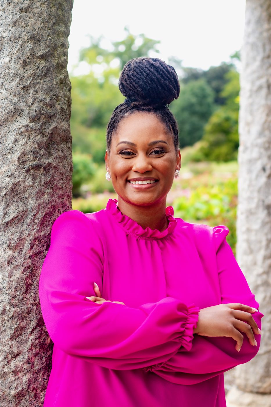 Confident portrait in a fuchsia blouse against garden columns