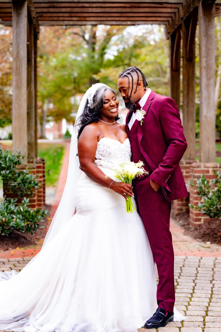 Bride and groom in burgundy suit sharing a moment